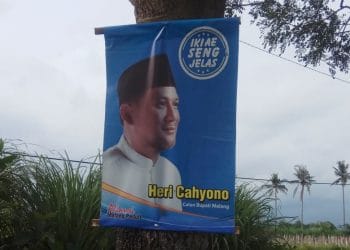 Banner Heri Cahyono 'Calon Bupati Malang' yang dipasang di pohon dengan cara dipaku