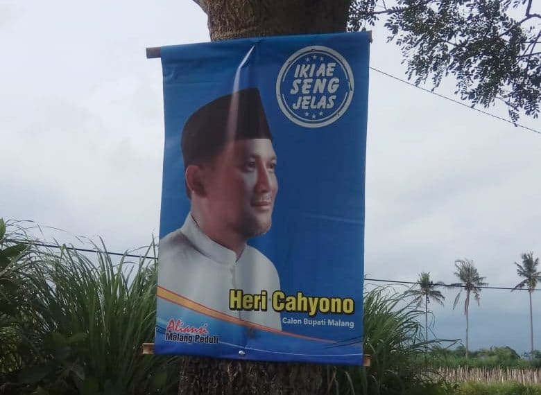 Banner Heri Cahyono 'Calon Bupati Malang' yang dipasang di pohon dengan cara dipaku