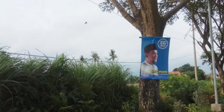 Banner Heri Cahyono 'Calon Bupati Malang' yang dipasang di pohon dengan cara dipaku