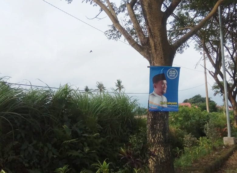 Banner Heri Cahyono 'Calon Bupati Malang' yang dipasang di pohon dengan cara dipaku