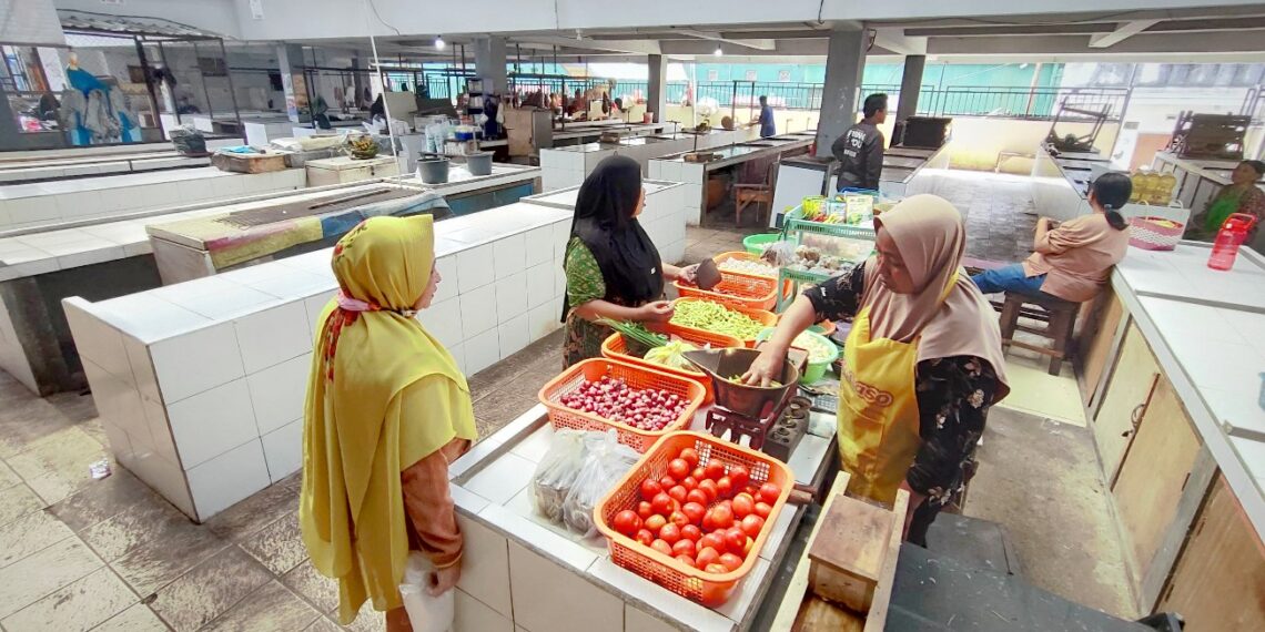 Lapak Zubaedah (jilbab coklat muda) di tengah-tengah lapak kosong di dalam Pasar Kebalen, Kota Malang. (Foto: Julian Sukrisna/Javasatu.com)