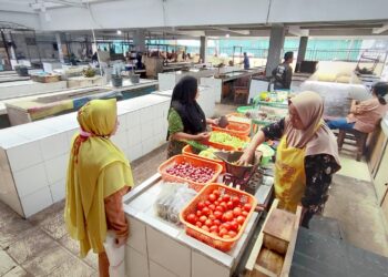Lapak Zubaedah (jilbab coklat muda) di tengah-tengah lapak kosong di dalam Pasar Kebalen, Kota Malang. (Foto: Julian Sukrisna/Javasatu.com)
